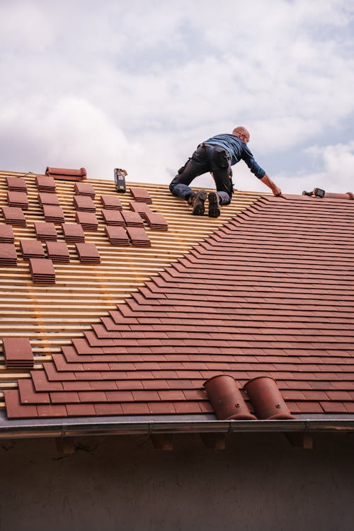 Professional roofer from Collins Roofing and Repair installing new red tiles on a residential home in Marion, SC, ensuring a streamlined replacement process.